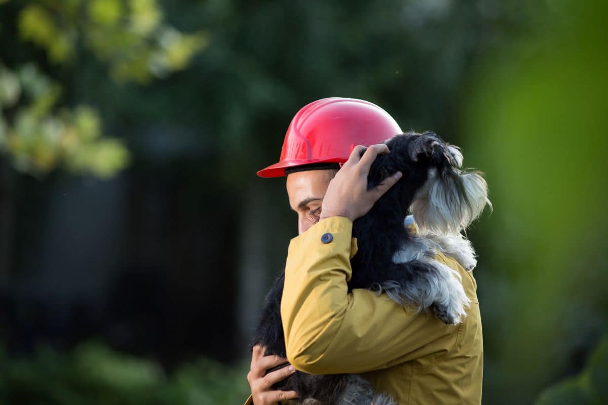 Sauveteur-tient-chien-dans-bras Un sauveteur tient un chien noir et blanc contre lui