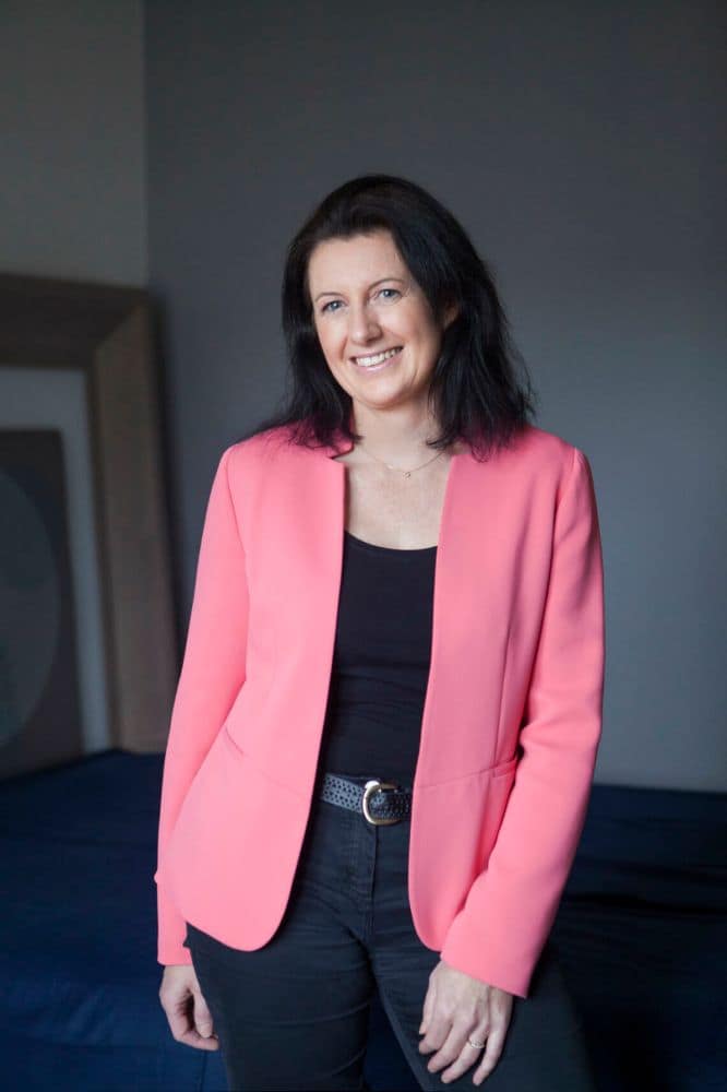 Céline Sissler-Bienvenu, fondatrice de Planimalia consulting, se tient debout, vêtue d'un blazer rose et d'un pantalon noir